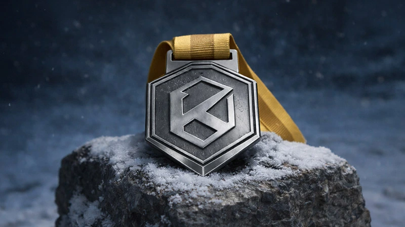 Elite edition Kolossal medal with gold ribbon displayed on a snow-covered stone in a cold mountain setting