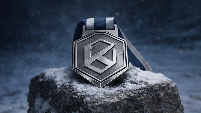 Standard edition Kolossal medal with blue ribbon placed on a snow-covered rock in a winter mountain scene