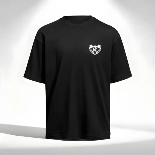 Black oversized t-shirt with small “Kolossal” emblem on the chest, featuring barbell and laurel logo, minimalist athletic streetwear.