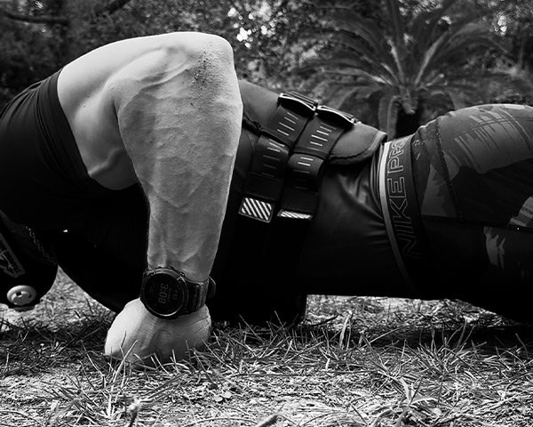 Athlete performing weighted push-ups outdoors with tactical vest, representing discipline and controlled effort in the Kolossal Hybrid System.